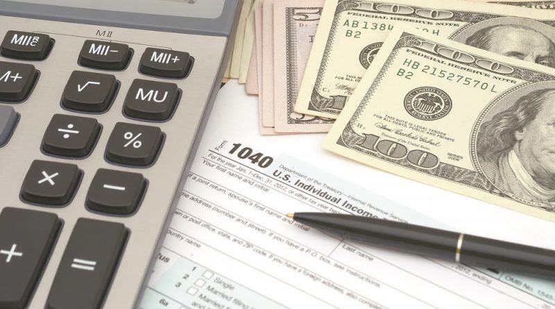 calculator, pen, $100 bills, and 1040 tax form
