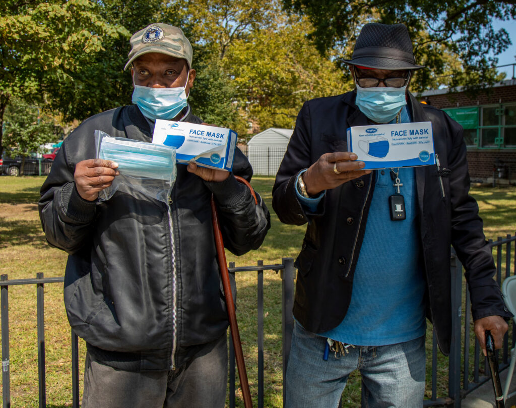 two men holding up boxes of face masks