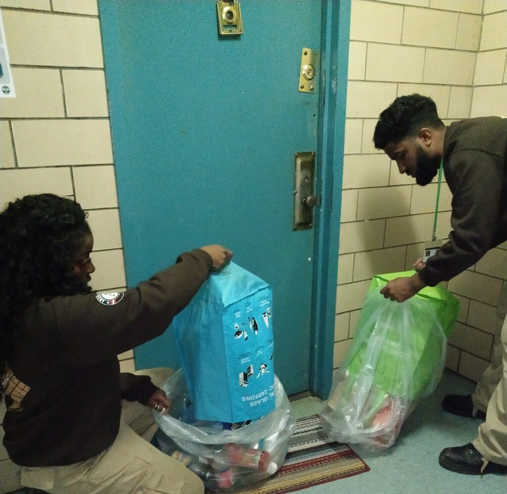 two people collecting recyclables from outside an apartment door.