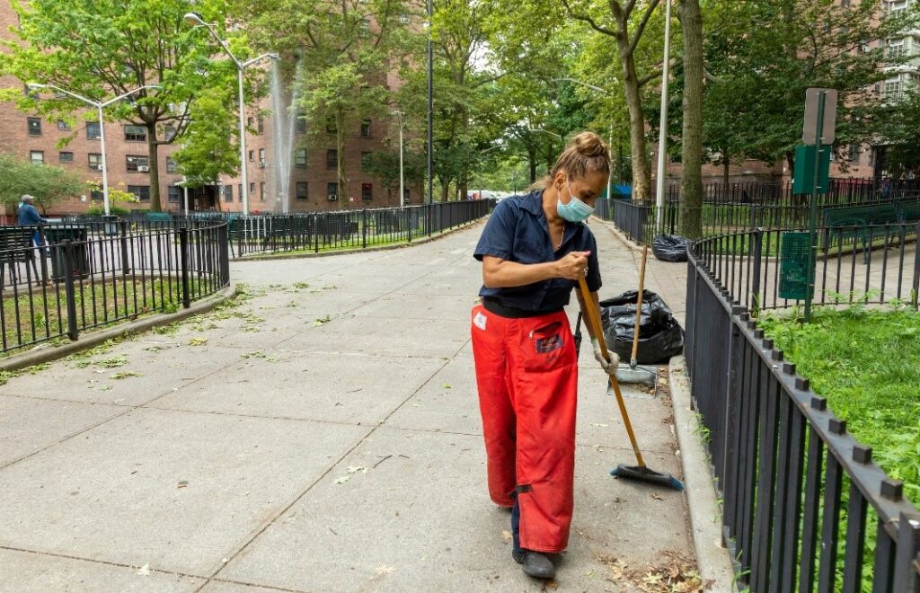 female employee sweeping building grounds