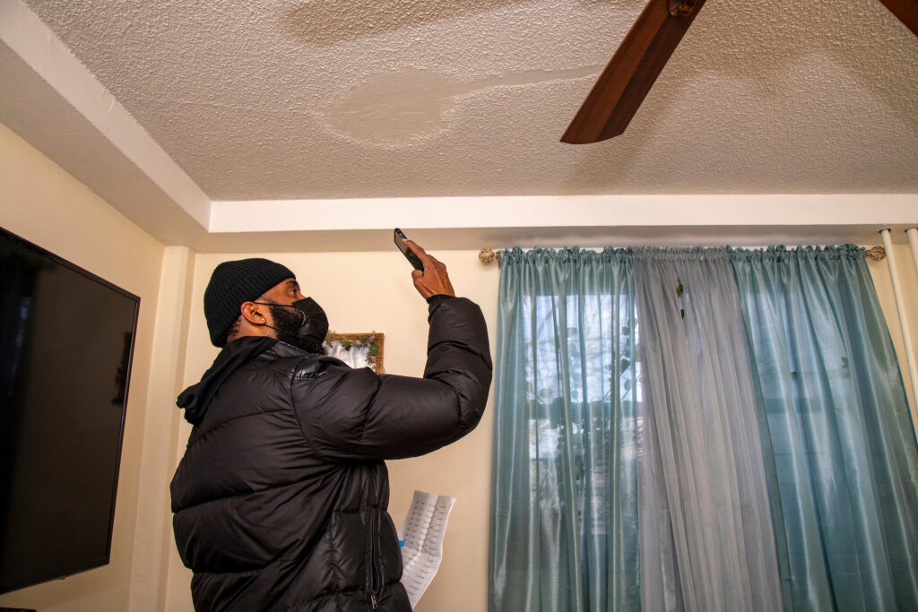 man taking a photo of ceiling with smartphone as part of visual paint inspection