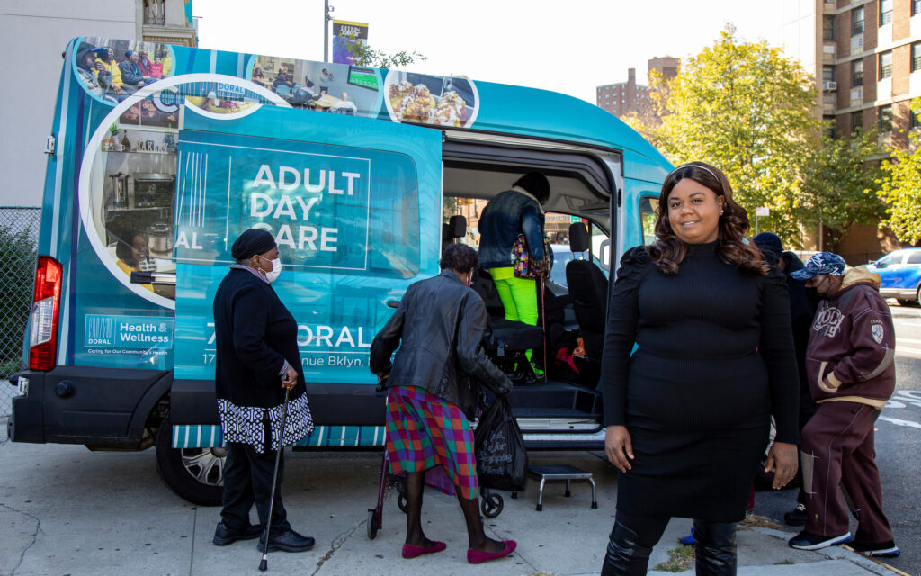 woman standing in front of a van with older adults getting on