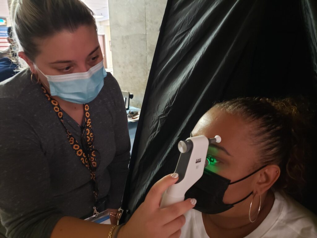 woman receiving eye exam from another woman