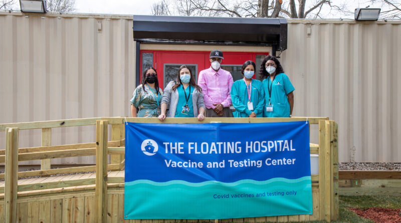 group of people wearing medical scrubs standing in front of shipping container clinic