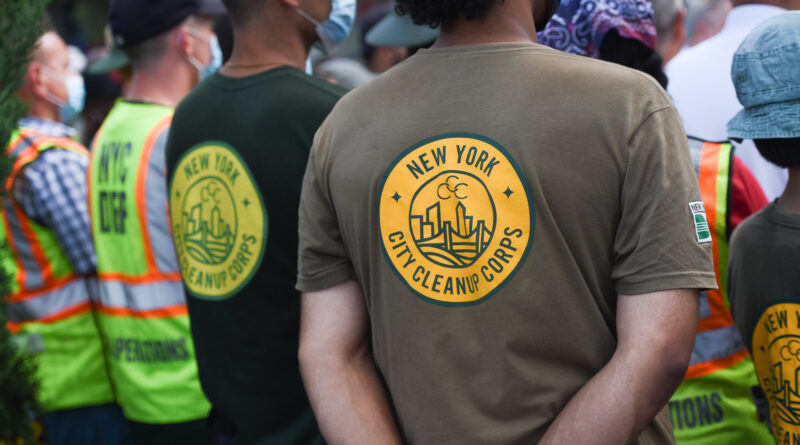 group of people with their backs to the camera wearing City Cleanup Corps shirts