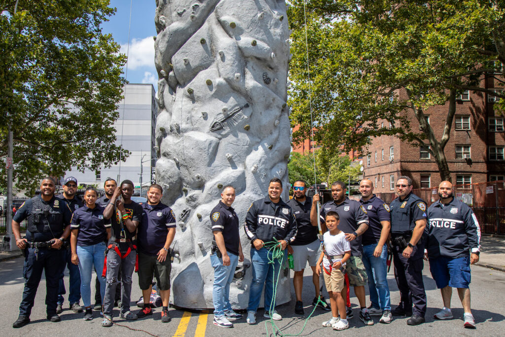 group of people standing in front of rock climbing structure