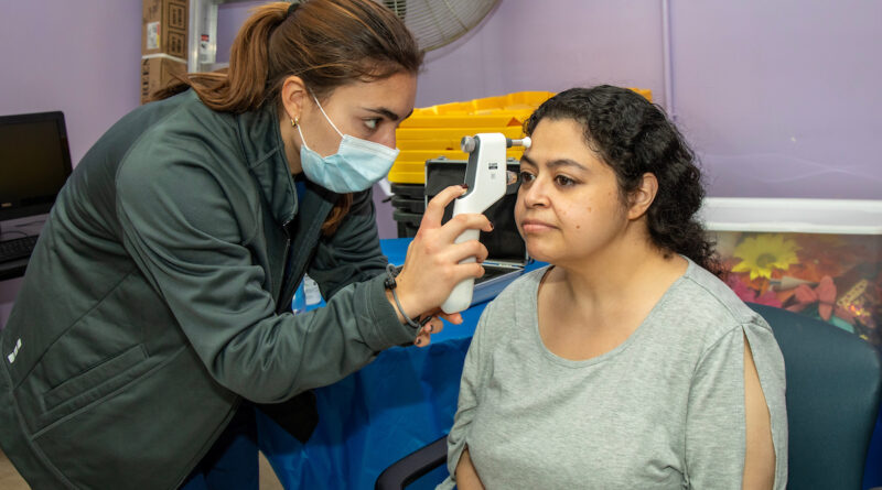 woman receiving eye screening from another woman
