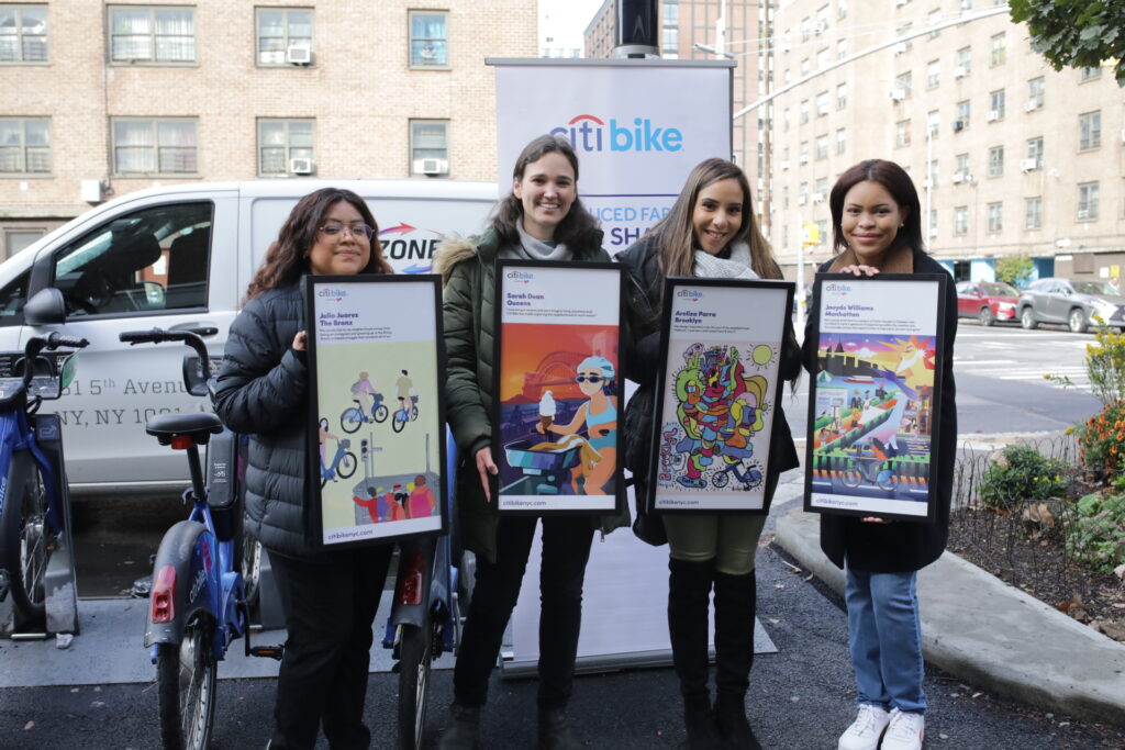 four women holding framed posters