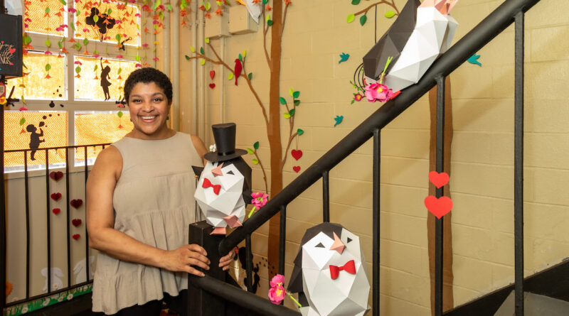 woman standing in hallway with paper art, including penguins