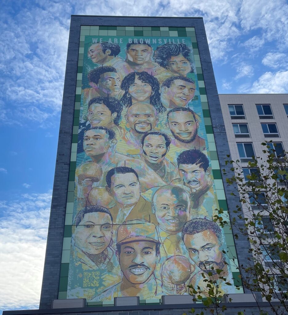 Image of a mural entitled 'We are Brownsville' on the side of a building in Brownsville. The mural, created by artist William “GoodWill” Ellis, celebrates 17 renowned individuals with roots in the community, including Lisa Kenner.