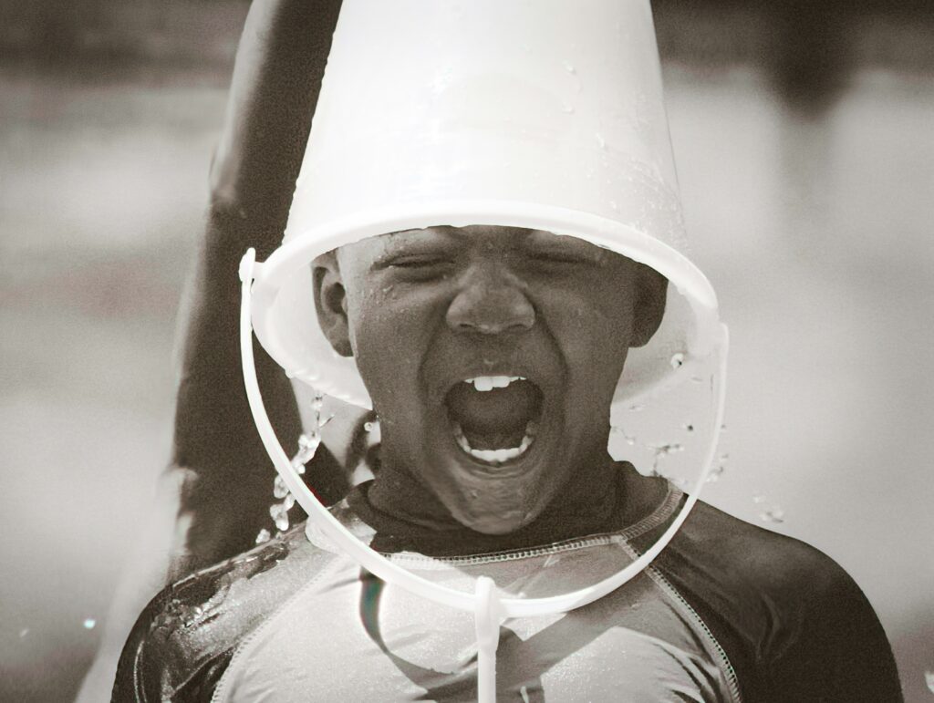 black and white photo of little boy with bucket on his head