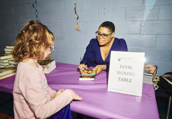 woman signing a book for a child