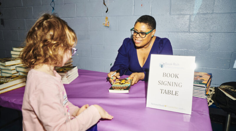 woman signing a book for a child