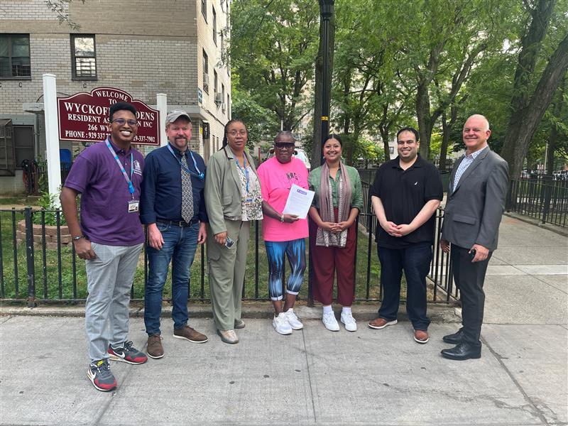 people standing in front of a building and a sign for Wyckoff Gardens