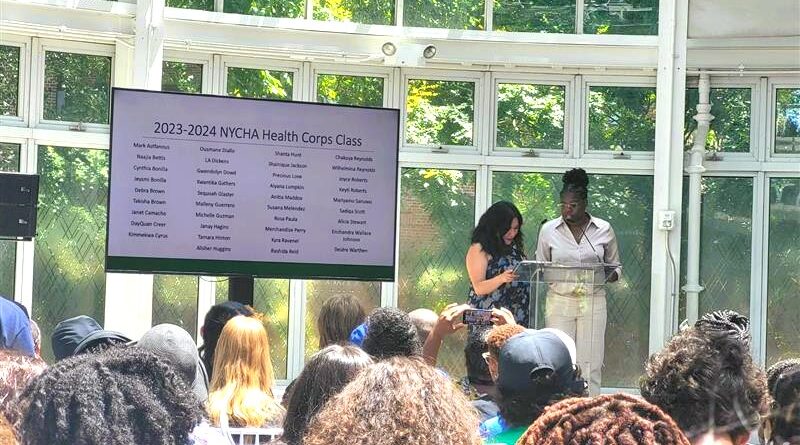 two women on stage, a screen on stage has the words 2023-2024 NYCHA Health Corps Class with a list of names