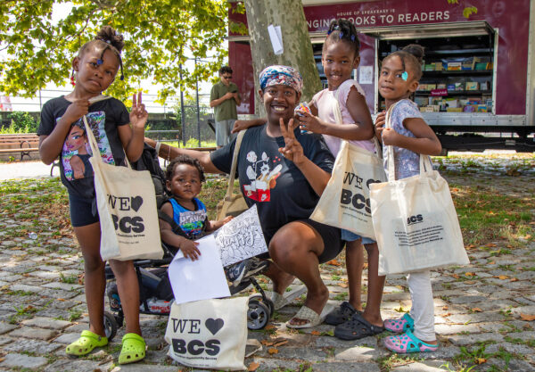 woman with four children who are all holding totebags