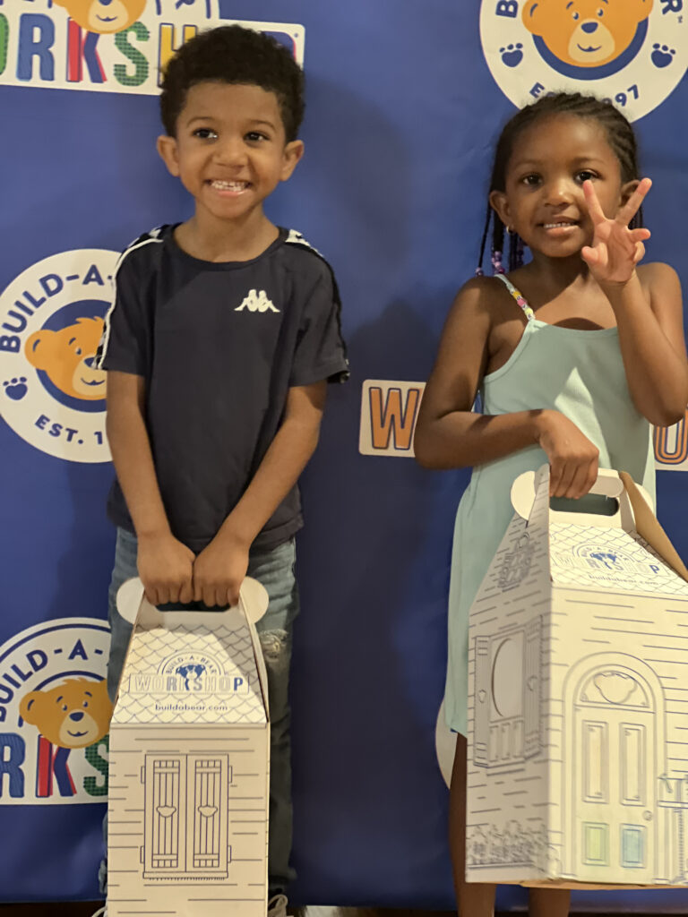 two children holding boxes with teddy bears inside