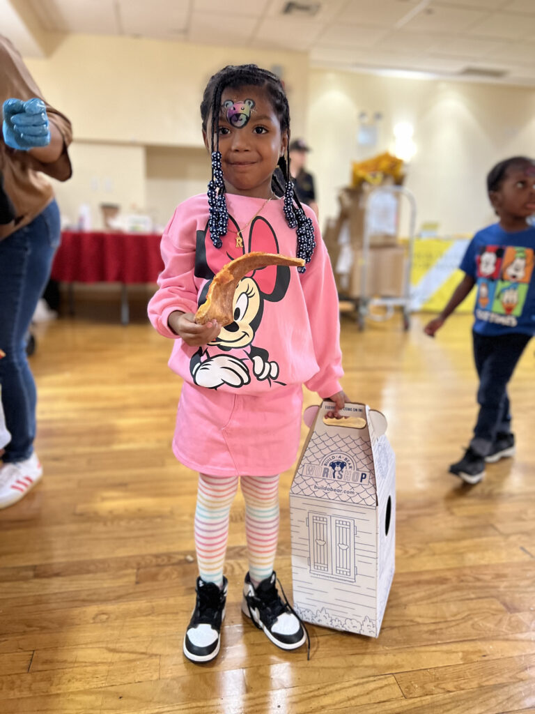 child holding a box and slice of pizza