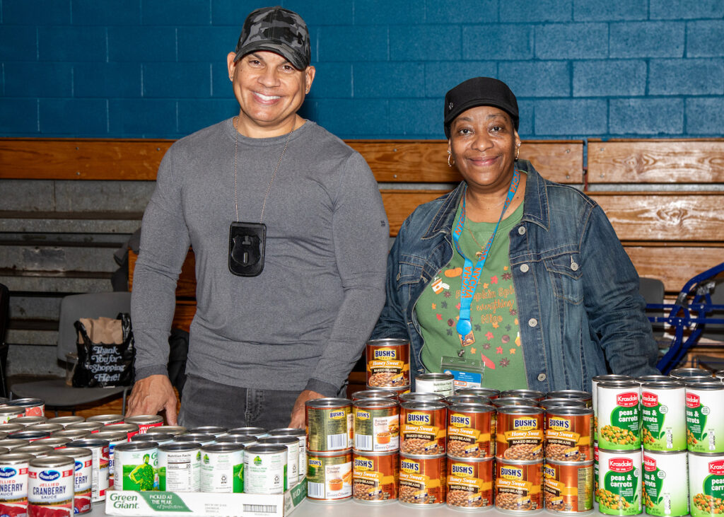 two people standing behind a table filled with canned goods