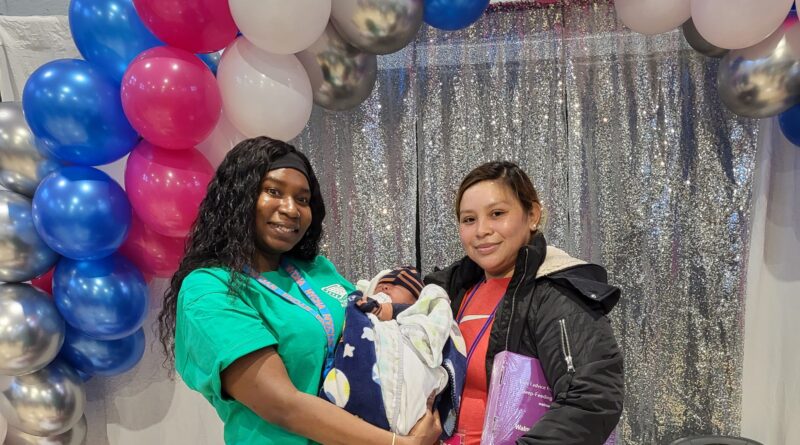 two woman, one holds a baby
