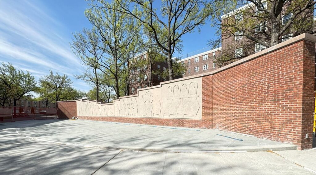 brick wall with frieze of people that look like they're dancing