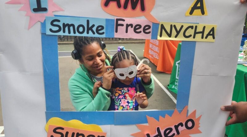 two people behind Smoke Free NYCHA sign