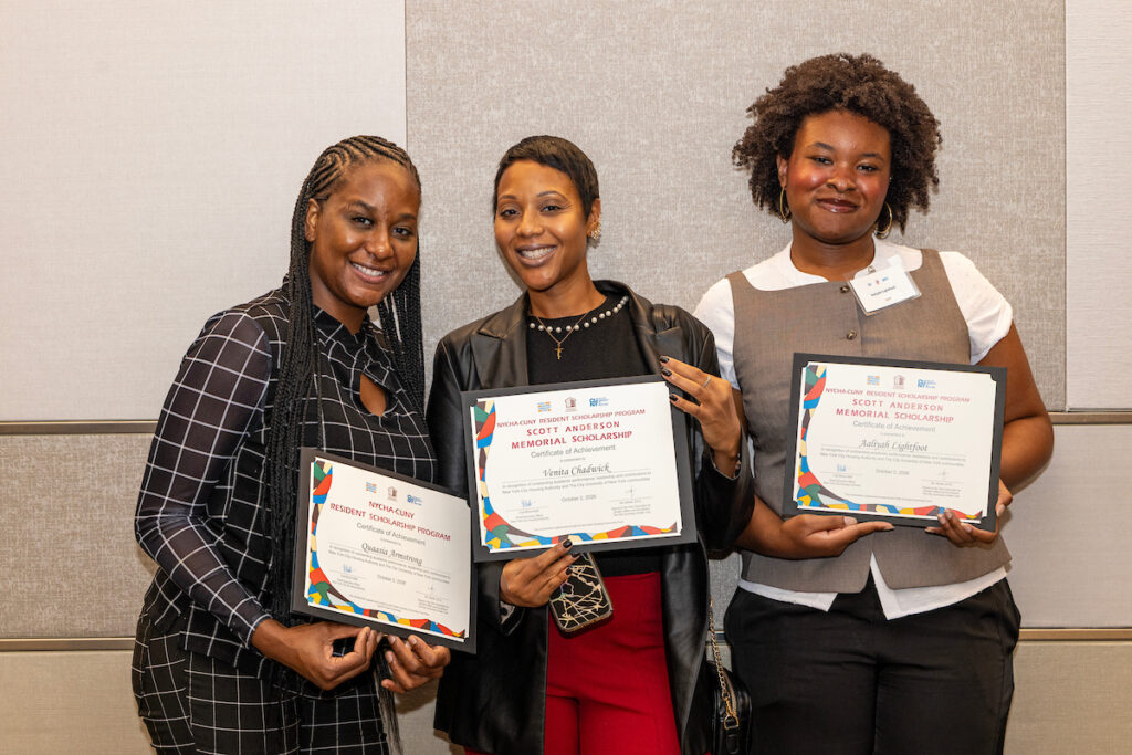 Three individuals stand together, each holding a framed certificate from the NYCHA-CUNY Resident Scholarship Program, smiling for the camera.