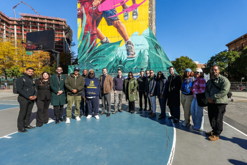 group of people standing in front of a colorful mural