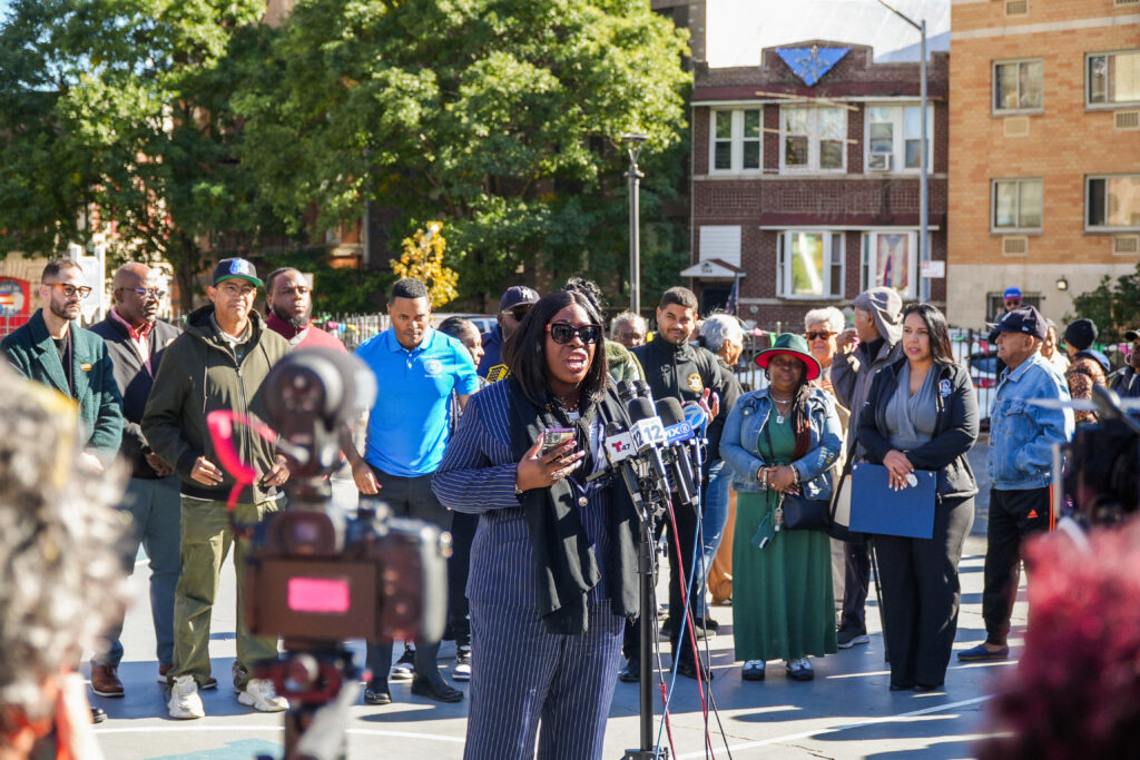 woman speaking at microphones surrounded by people