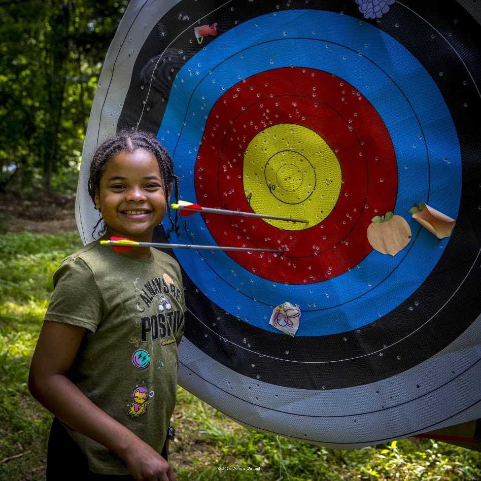 young girl standing in front of archery target