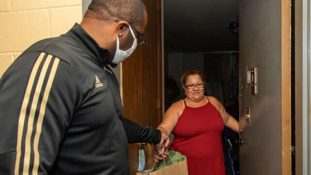 Distribution of turkeys, produce, and food vouchers to senior residents of Claremont Consolidation. man hands woman groceries