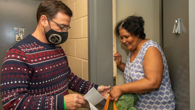Claremont Consolidation turkeys, bags of produce and food vouchers to senior residents man hands woman bag of groceries