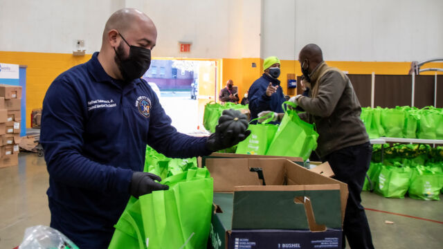 Turkey and produce giveaway at Melrose Classic Community Center. man sorting vegetables into bags