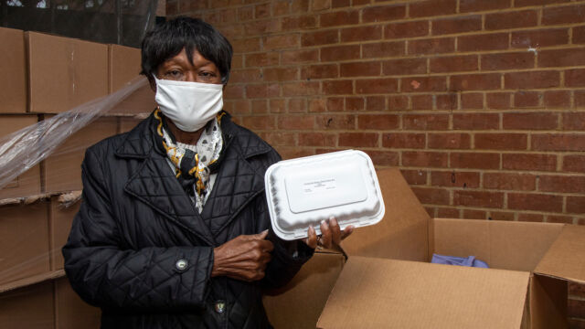 Claudia Coger, President of the Astoria Houses Resident Association, was instrumental in working with Urban Upbound to help provide residents with meals. woman holding up meal container