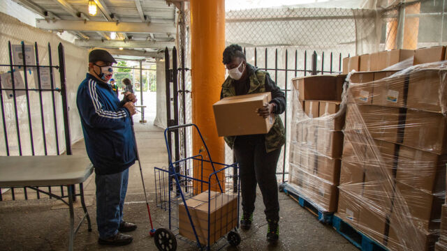 Astoria Houses and Urban Upbound Gas Outage Food Distribution woman putting box into man's shopping cart