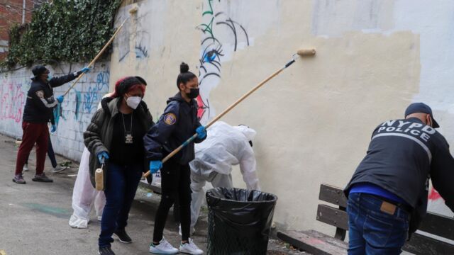 group of people painting over graffiti