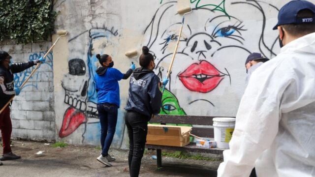 group of people painting over graffiti