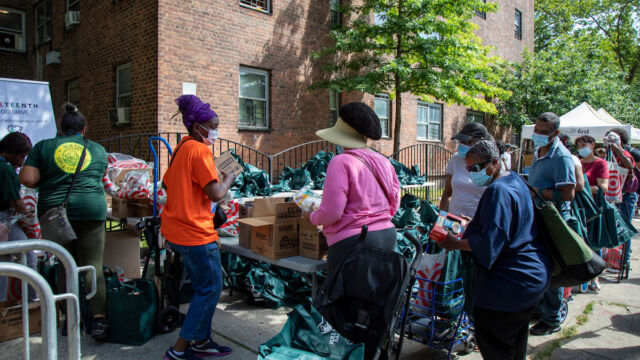 Residents wait to receive donated goods at the Juneteenth Food Drive. group of people