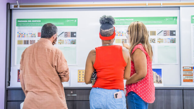 three people looking at a poster hanging up on a wall