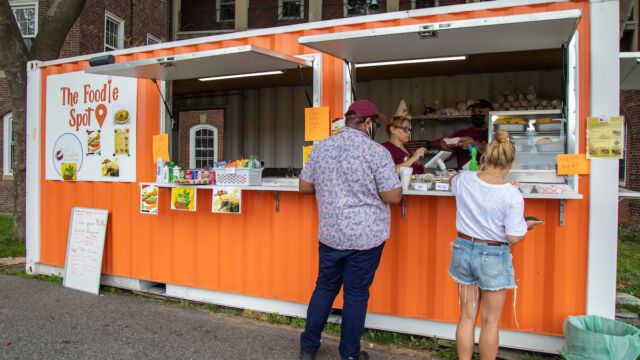 Serving customers at The Foodie Spot. food shipping container, people