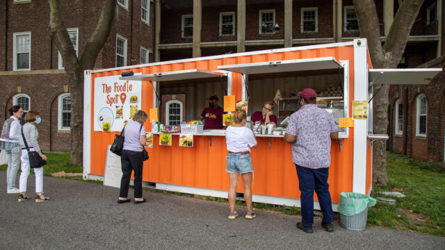 Serving customers at The Foodie Spot. food shipping container, people