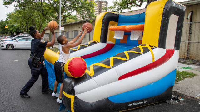 National Night Out at Linden Park woman police officer and child playing bouncy house basketball