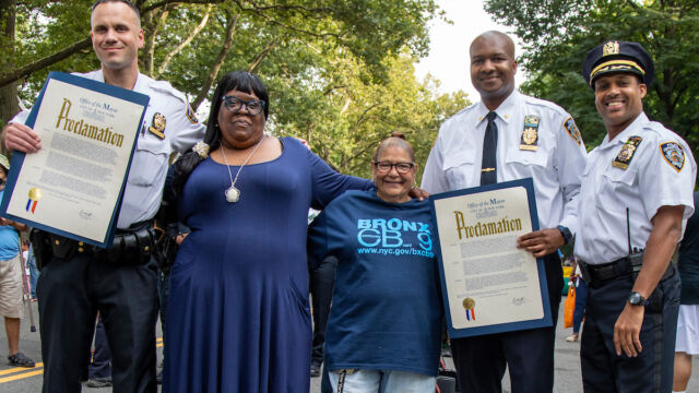 National Night Out Monroe Houses group of people, including two police officers holding official proclamations from the Mayor's Office