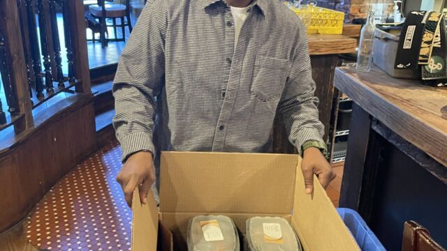 man holding a box of food containers for donation